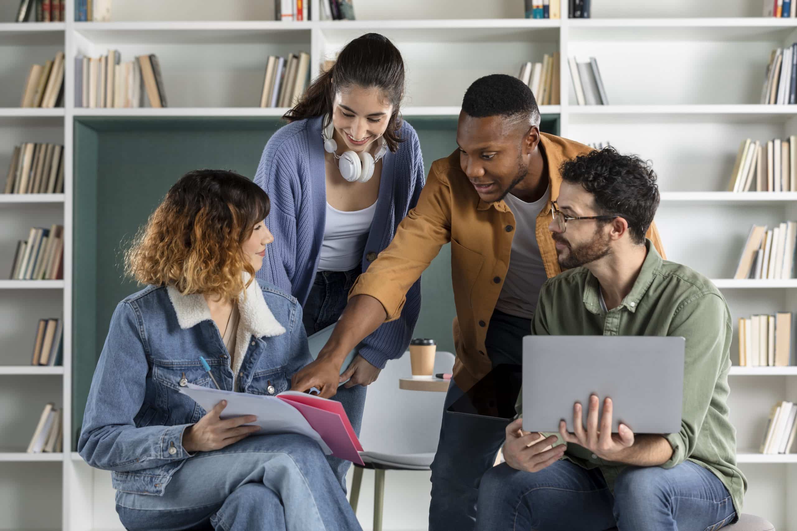 Atividade extracurricular: grupo com quatro pessoas trocando conhecimento enquanto utilizam um notebook para coletar informações.