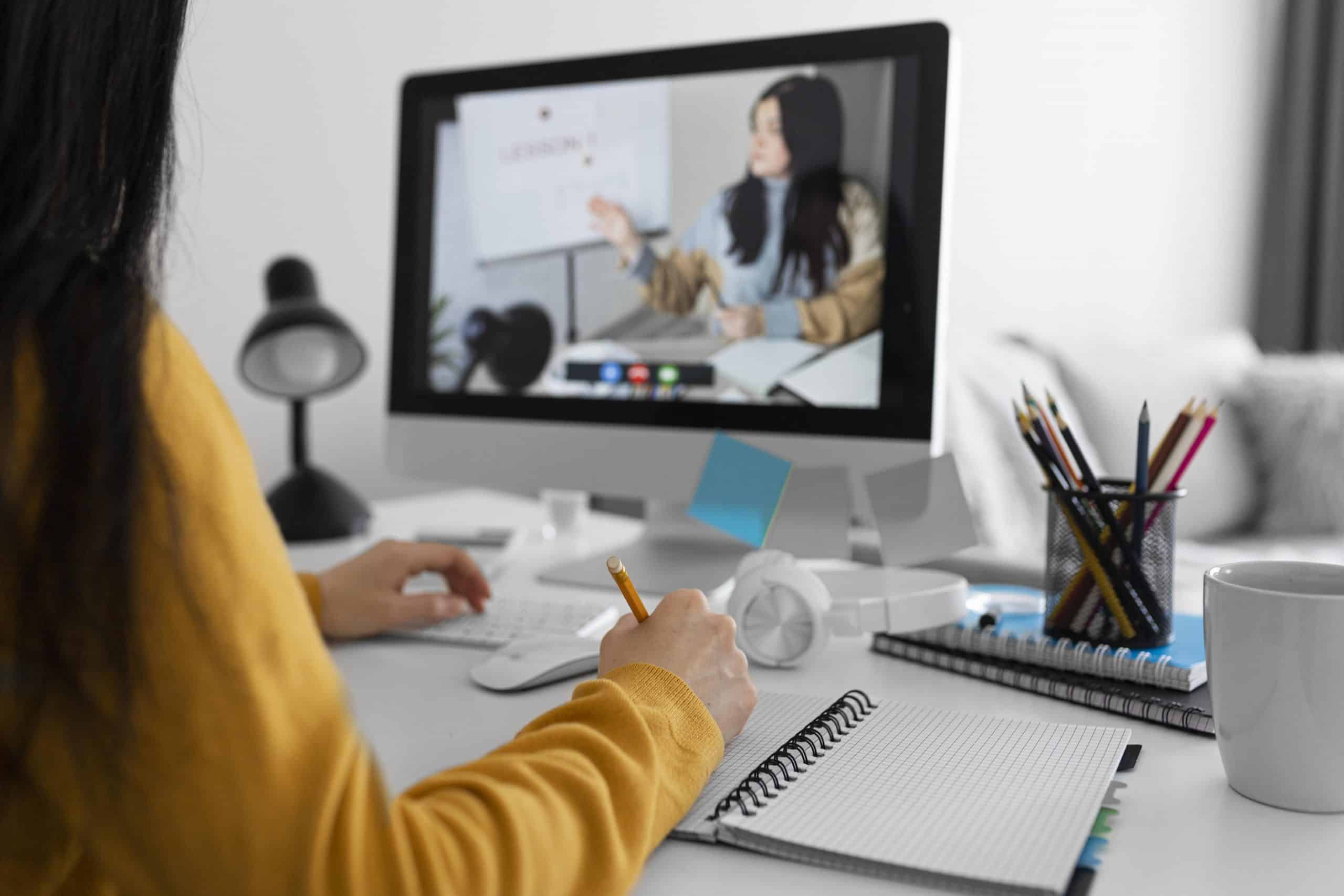 Faculdade online: aluna em frente ao computador assistindo uma vídeo aula.