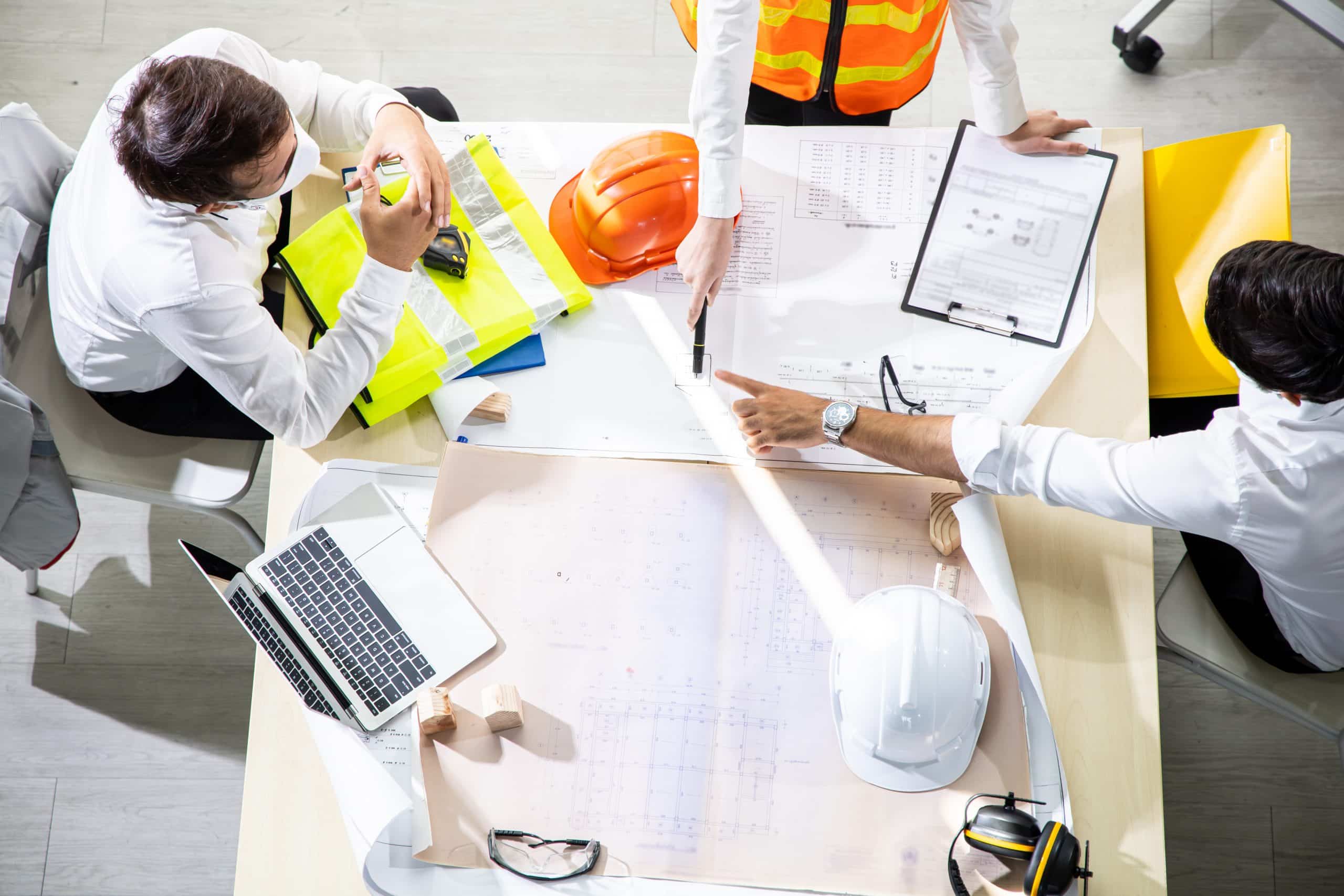 Áreas da engenharia: engenheiros ao redor de uma mesa com equipamentos de segurança e ferramentas da área