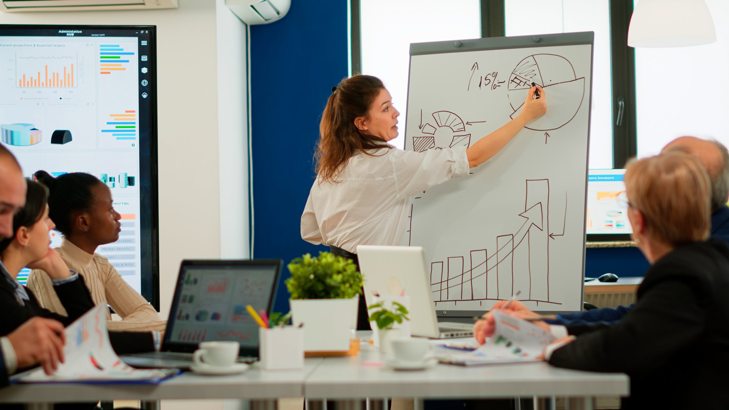 Várias pessoas reunidas analisando um quadro com gráficos