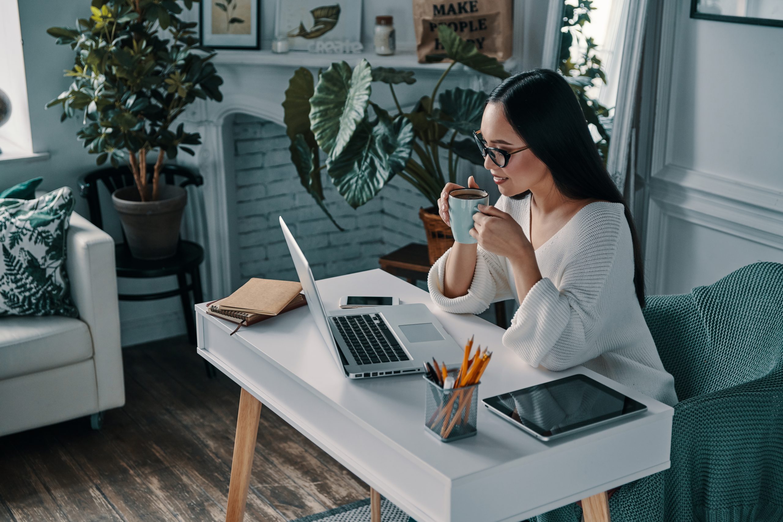 Mulher com uma xícara de café em frente ao computador