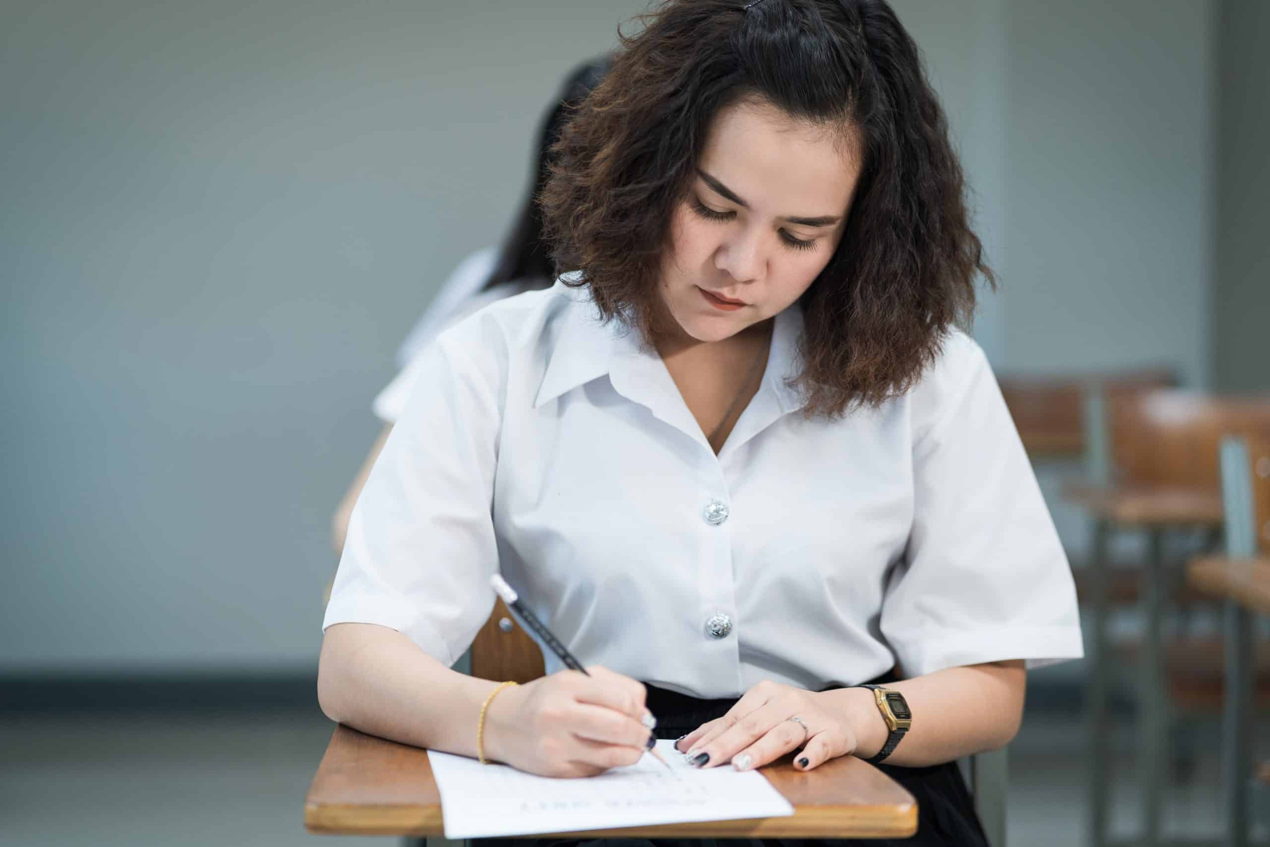 Mulher em uma sala de aula fazendo uma prova