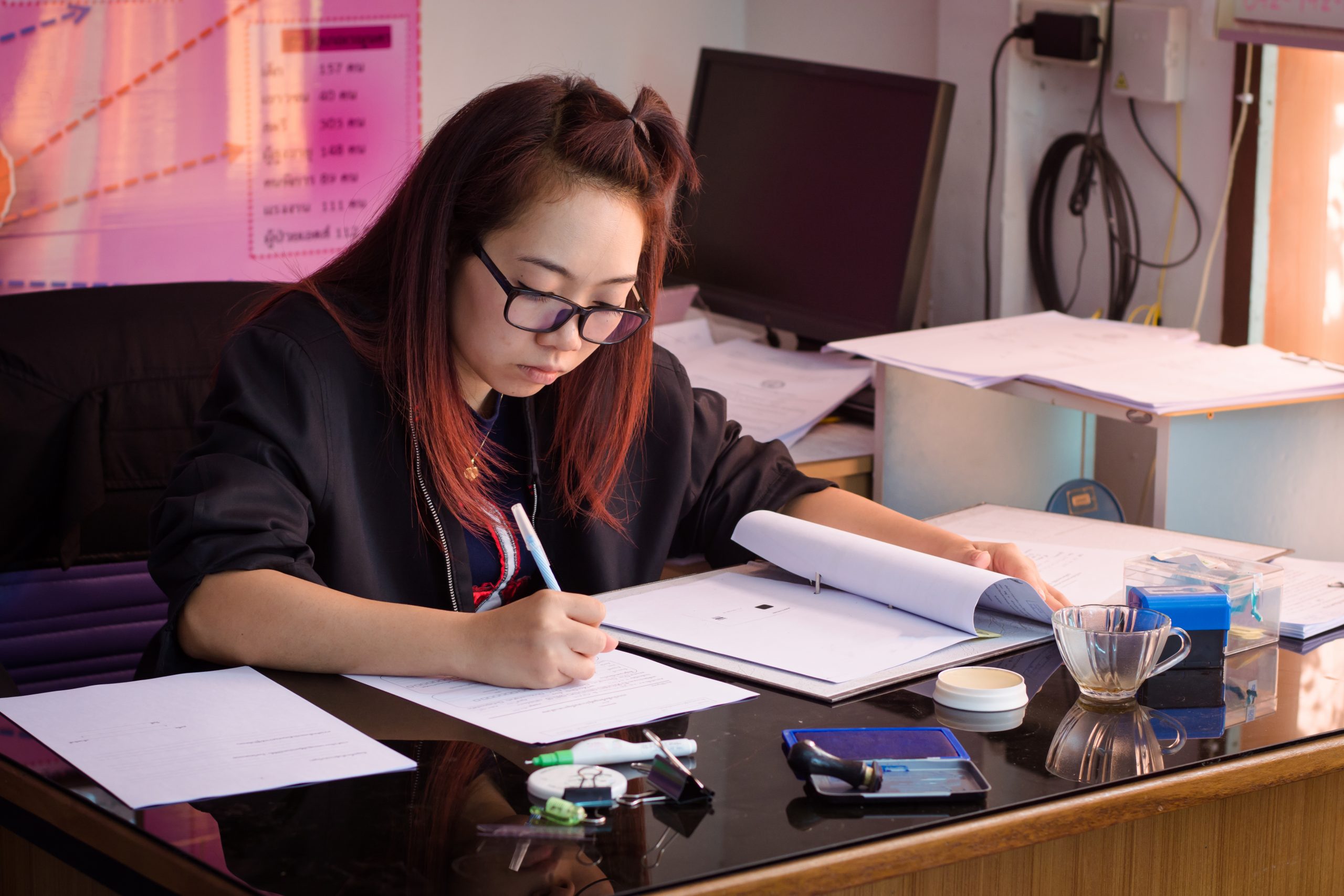 Menina de óculos estudando em um escritorio.