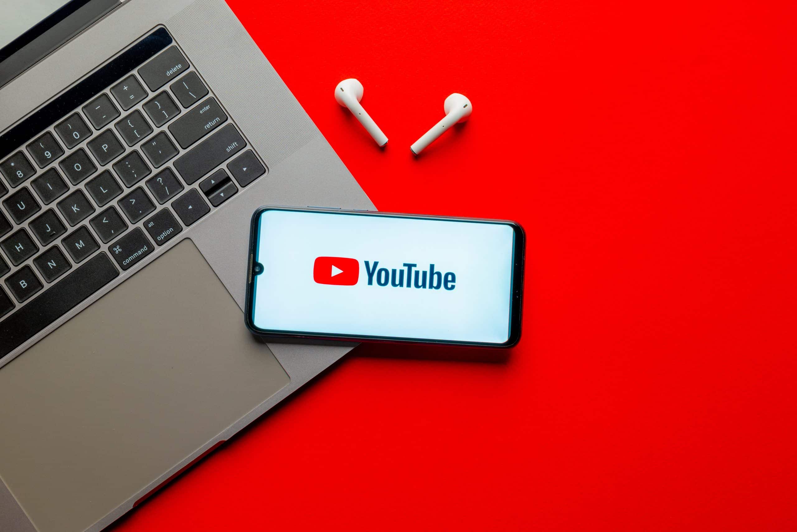 Mesa com um notebook e um celular com a logo do YouTube