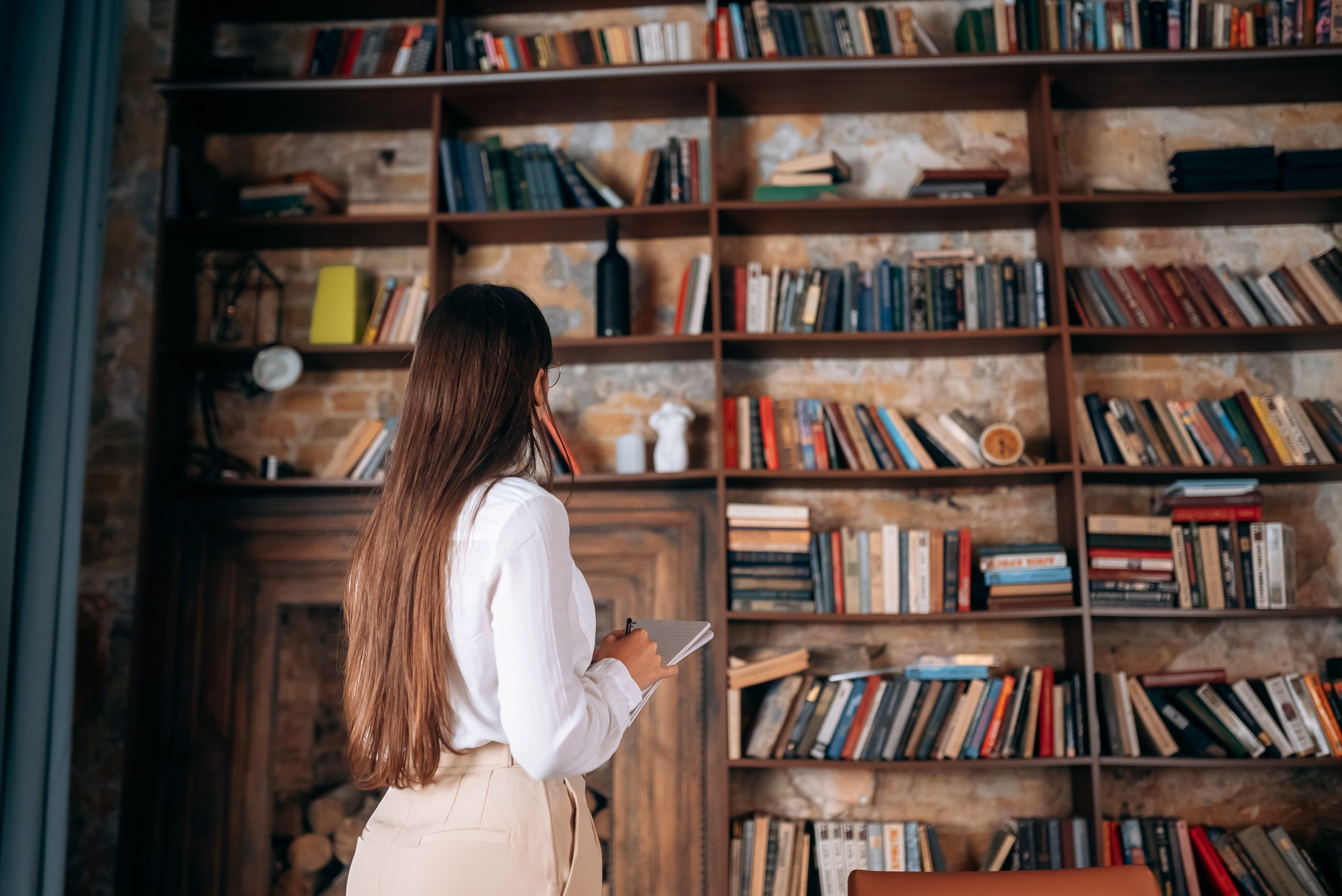 Mulher olhando para alguns livros em uma bibliote
