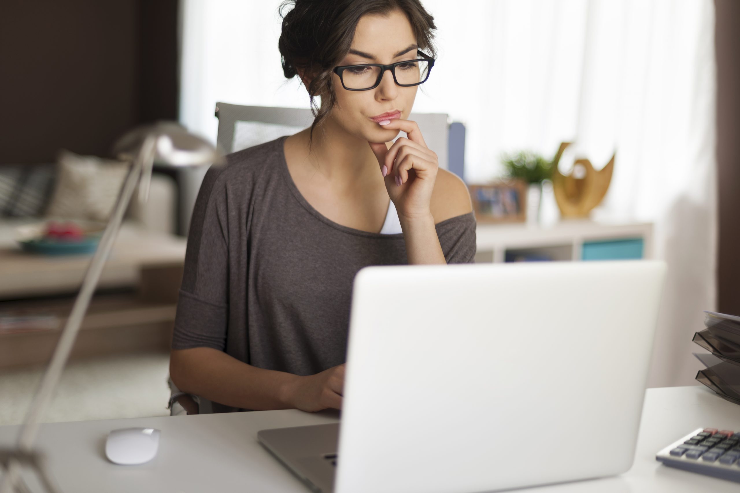 Mulher sentada em uma mesa, frente ao notebook