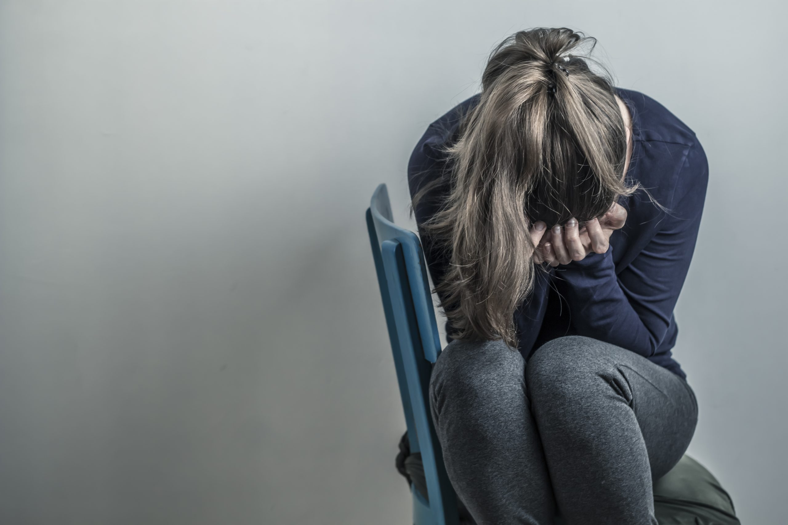 Mulher sentada em uma cadeira com a cabeça nas mãos