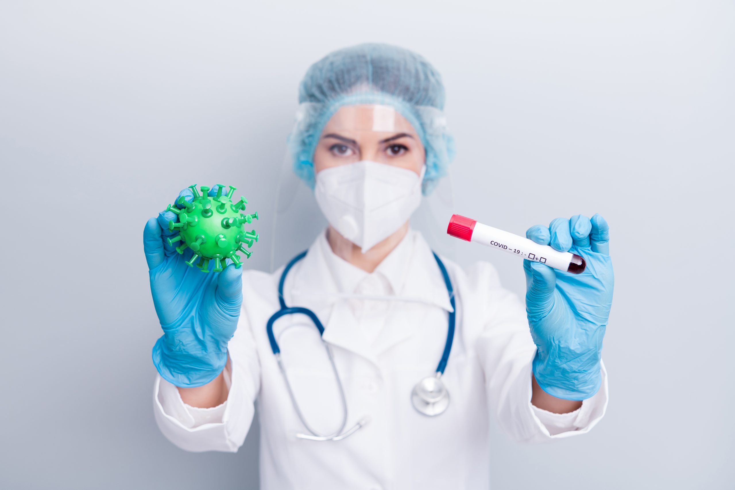 Médica de mascara segurando uma amostra de sangue