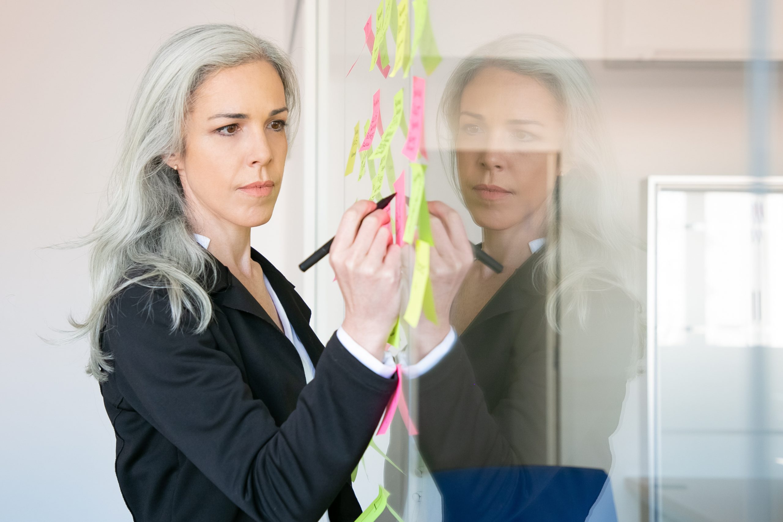 Mulher escrevendo em um quadro com alguns post-its