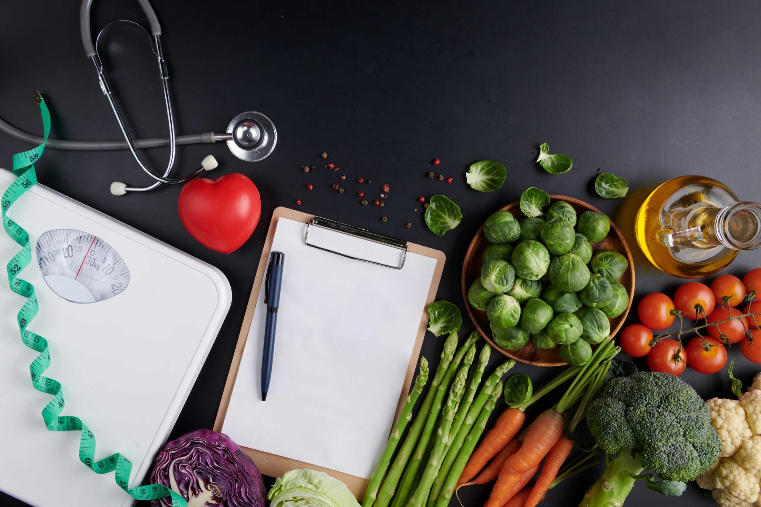 Alguns itens de nutrição em cima de uma mesa, frutas, legumes, prancheta.