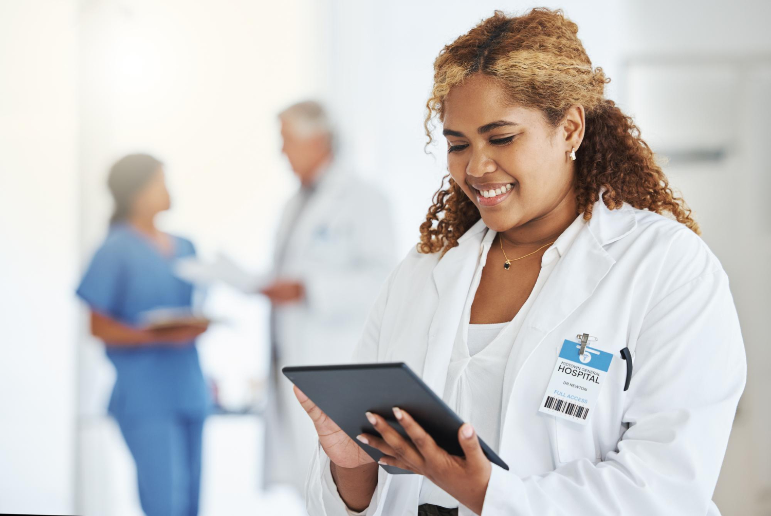 Mulher sorrindo com um tablet nas mãos em um hospital
