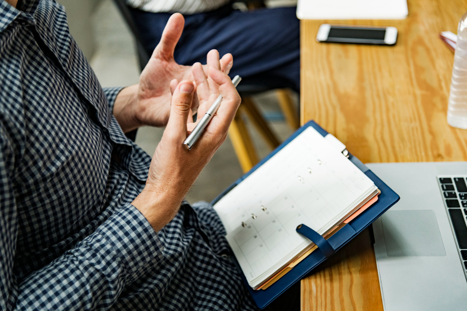 Mãos masculinas segurando uma caneta com uma agenda no colo
