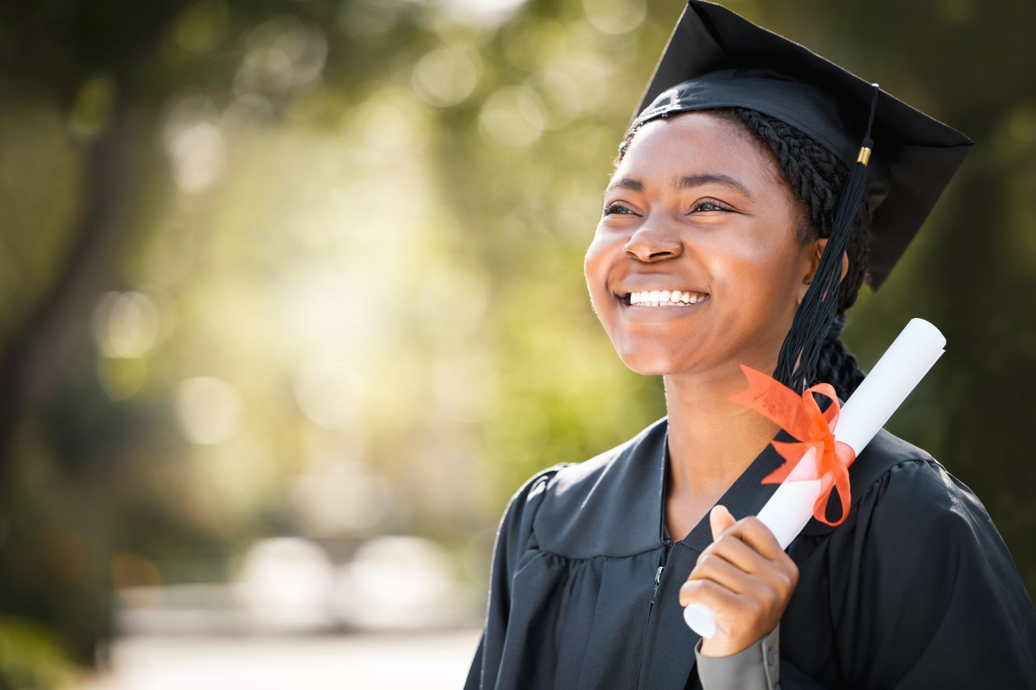 Jovem mulher sorrindo com um capelo e segurando um diploma