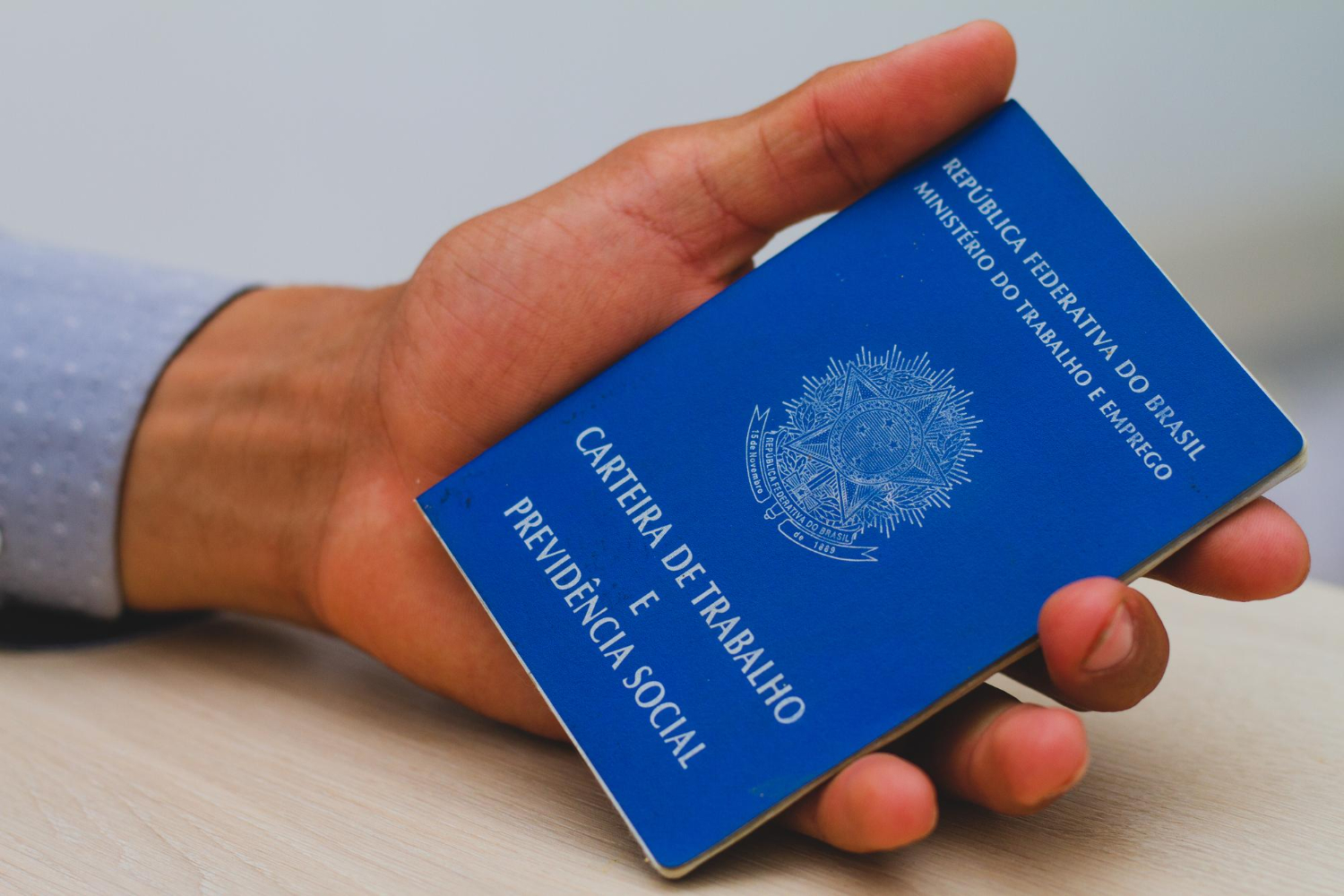 Mão masculina segurando uma carteira de trabalho