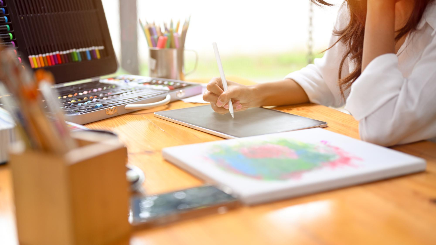 Mulher desenhando em um caderno em cima de uma mesa