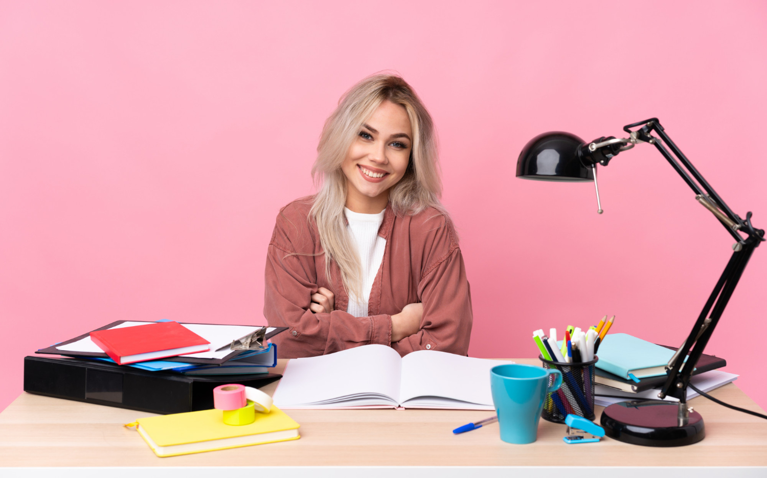 Jovem mulher em sua mesa de estudos, estudando para exercer uma das profissões para quem gosta de escrever.