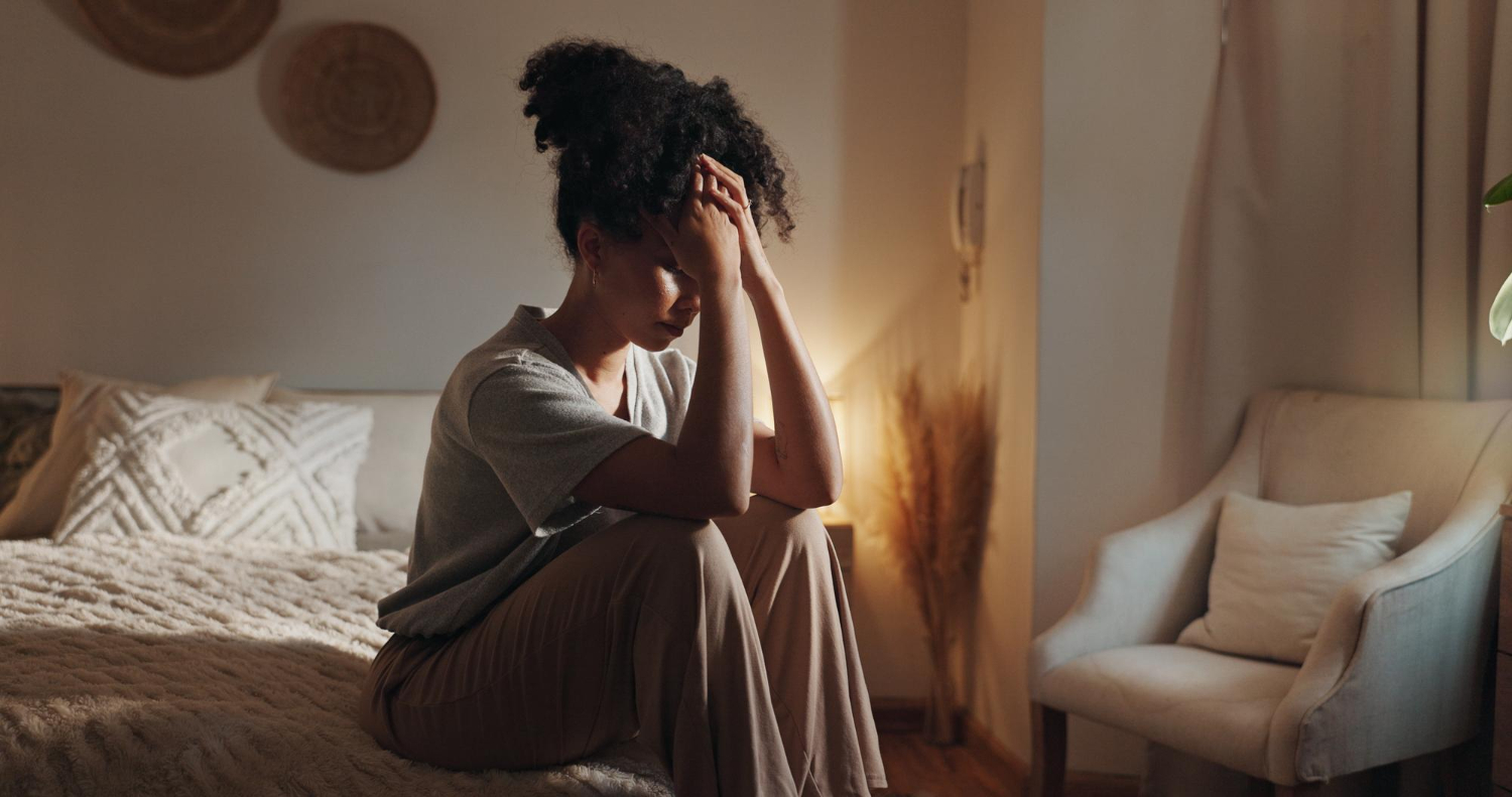 Jovem mulher com a cabeça entre as mãos pensando como controlar a ansiedade.