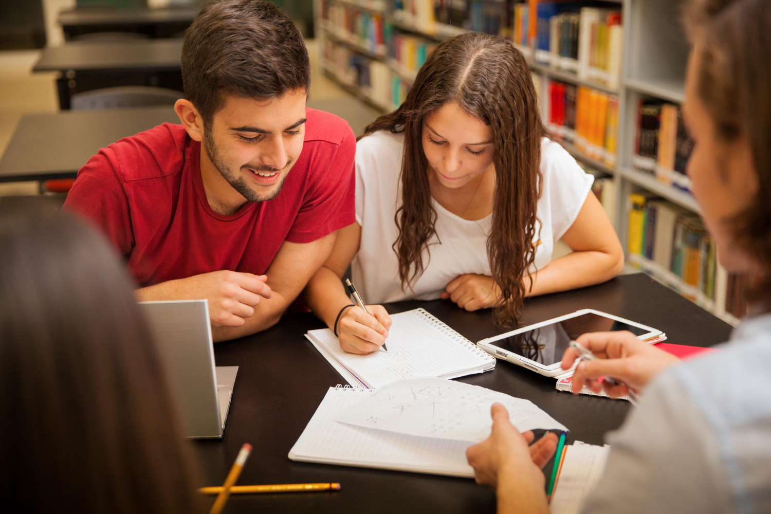 Grupo de jovens lendo sobre como estudar para concurso em uma biblioteca.