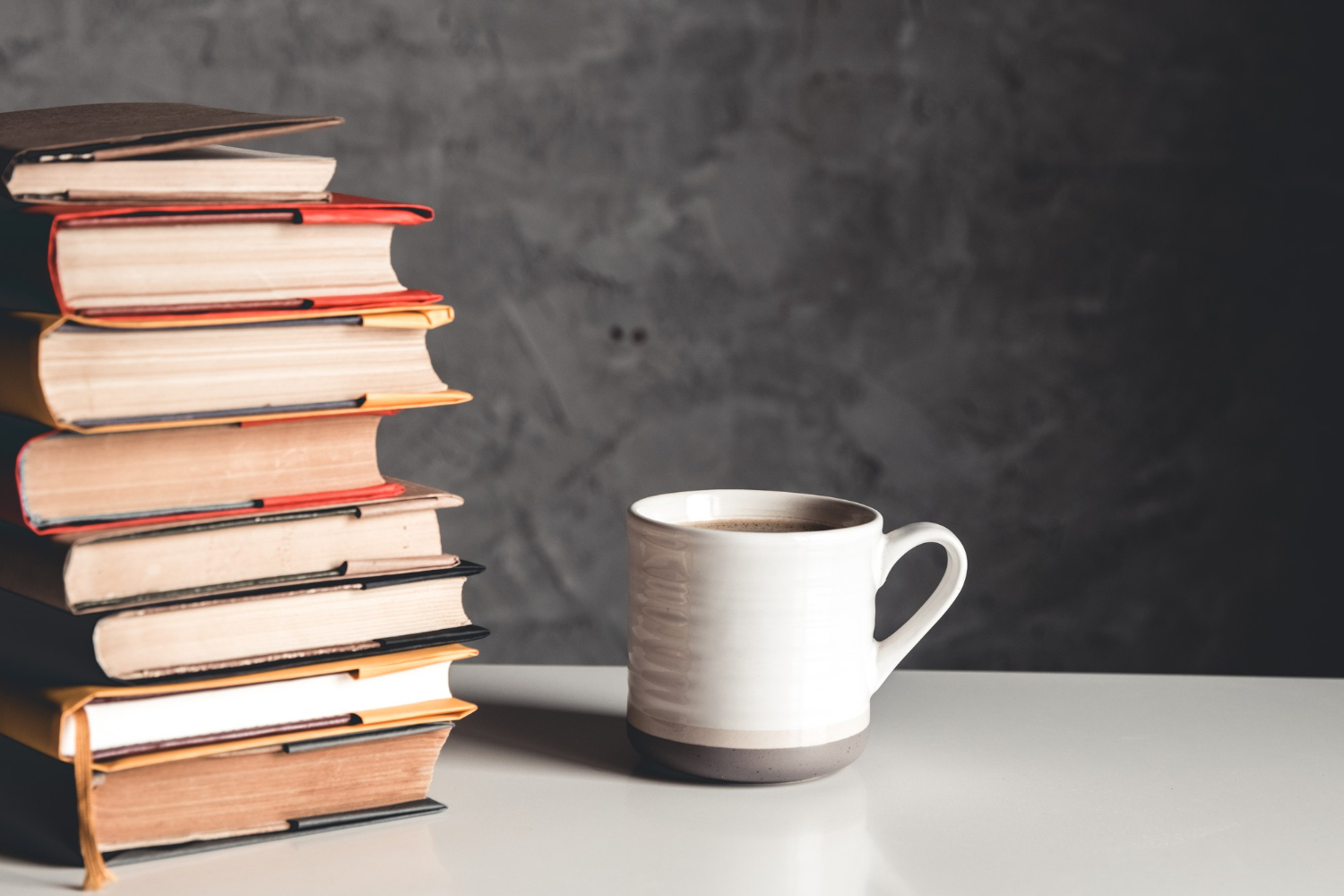 Livros de persuasão empilhados ao lado de uma caneca