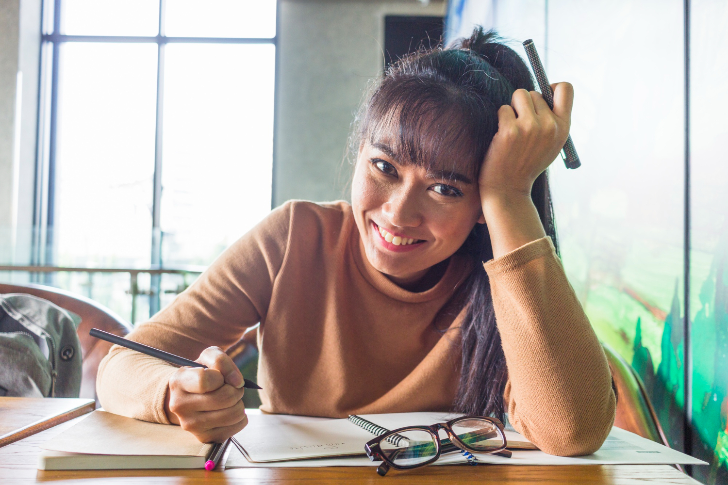 Jovem mulher sorrindo e estudando sobre vicios de linguagem.