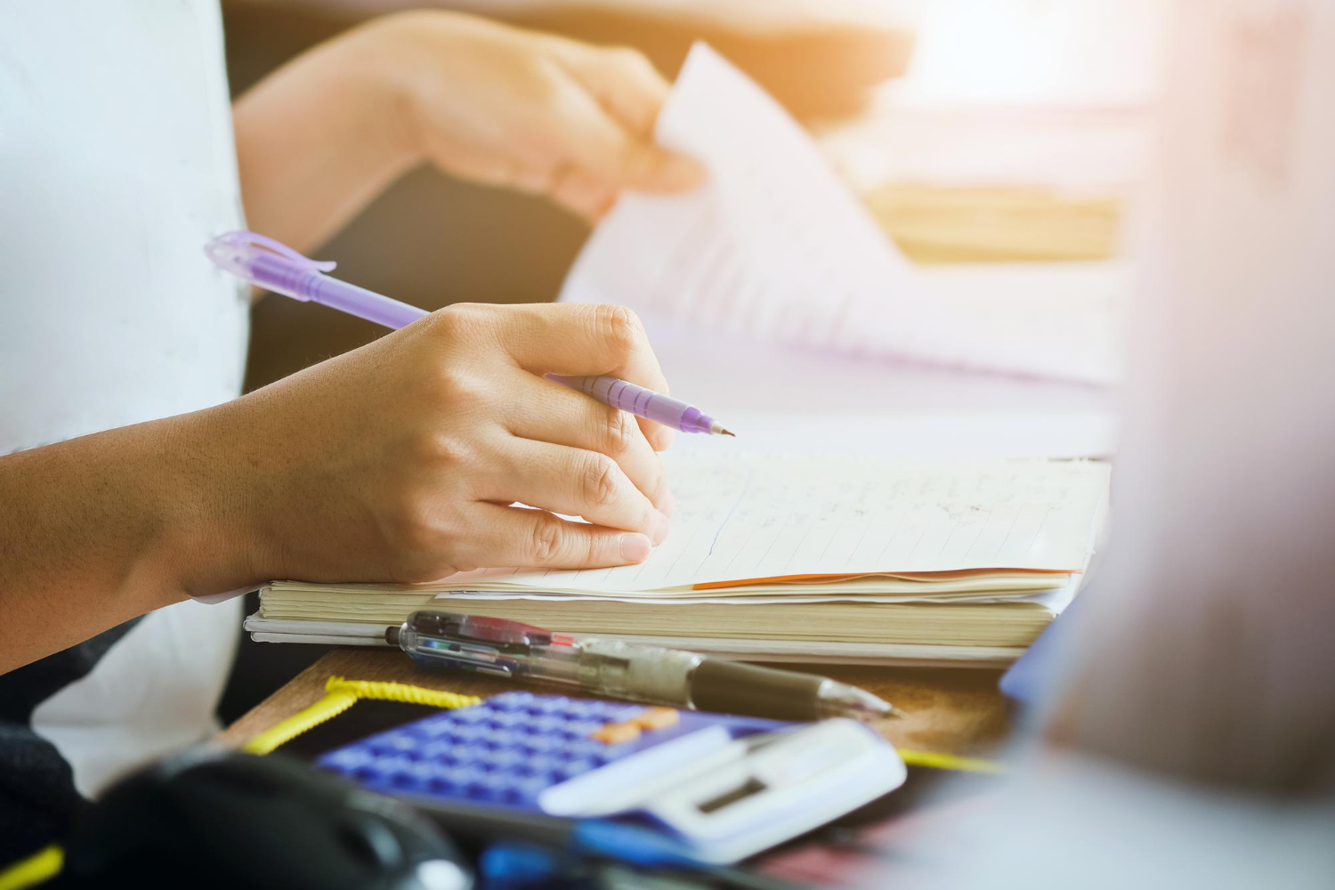 Mãos masculinas escrevendo em um caderno para as provas finais.
