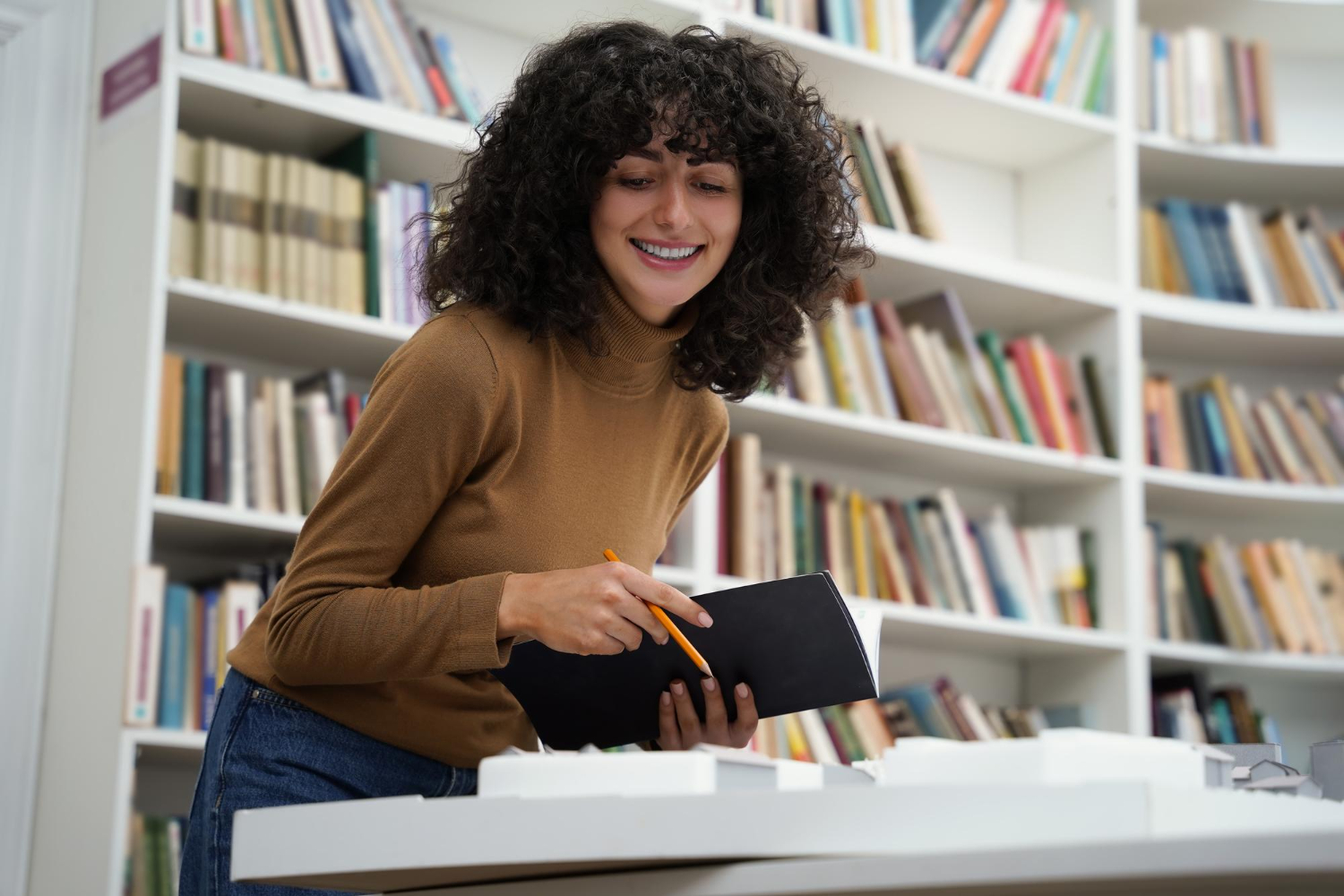 Mulher sorrindo e lendro livros para melhorar a comunicação.