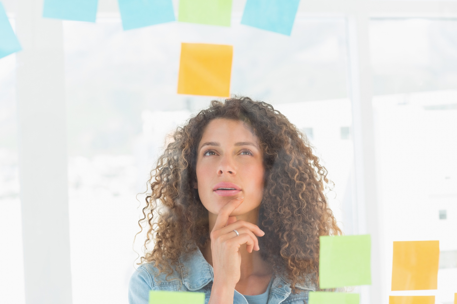 Jovem mulher olhando para vários post-its pensando em resolução de problemas.
