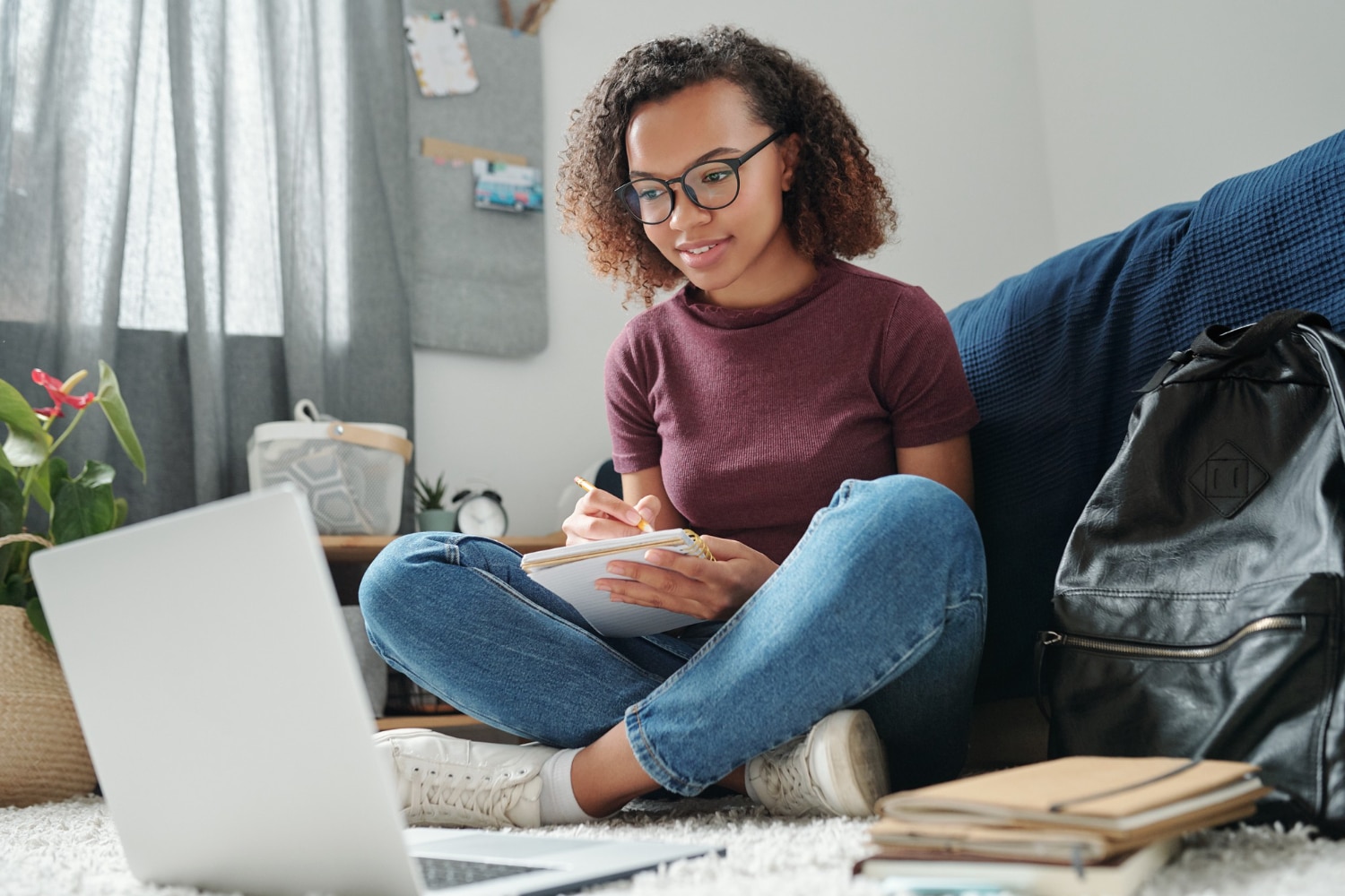 jovem adulta sentada no chão do quarto estudando
